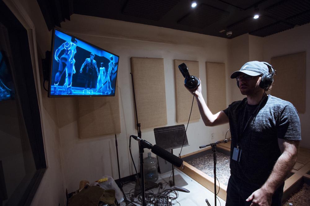 Man with headphones looking at a screen to record foley